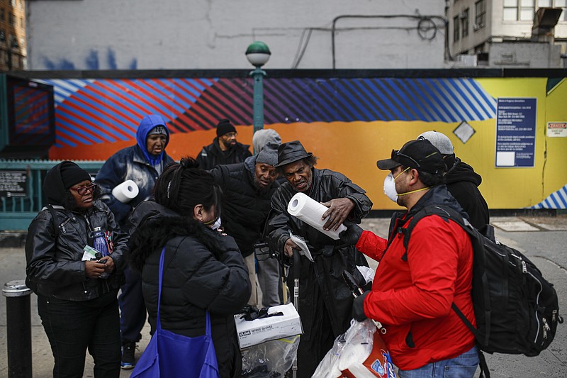 Felix Guzman, right, and his wife Virna wear protective gloves and masks due to COVID-19 concerns as they hand out disposable gloves and sanitizing wipes to a group of people who are homeless on 34th Street, Saturday, March 21, 2020, in New York. "I work for a supermarket and I know how people get crazy because we don't have any wipes," said Virna Guzman. "My husband and I decide to come around and do something for them. I wish we could the more." (AP Photo/John Minchillo)

