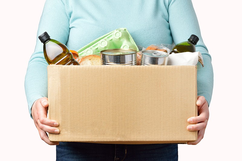 Volunteer with donation box with foods on white background food tile volunteer food box donation / Getty Images
