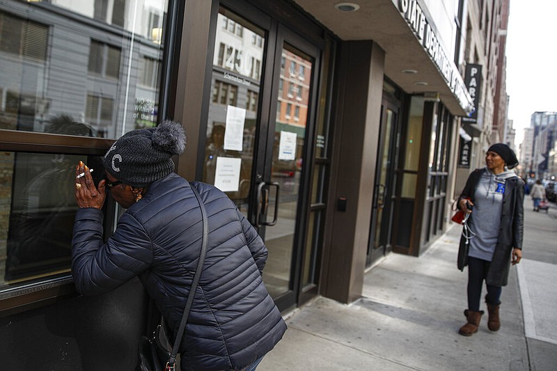 Visitors are unable to gain access to the Department of Labor due to closures over coronavirus concerns, Wednesday, March 18, 2020, in New York. Applications for jobless benefits are surging in some states as coronavirus concerns shake the U.S. economy. The sharp increase comes as governments have ordered millions of workers, students and shoppers to stay home as a precaution against spreading the virus that causes the COVID-19 disease. (AP Photo/John Minchillo)