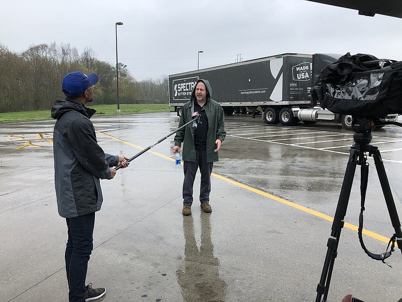 WRCB-TV 3 reporter Travis Cummings interviews a subject using a microphone on a boom pole fashioned by station Chief Photographer Lee Broome last week as a way to keep reporters in the field and subjects a safe distance from each other. / Photo contributed by Lee Broome