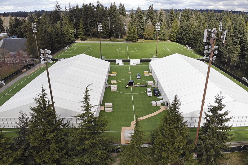 n this photo taken Tuesday, March 24, 2020, two massive temporary buildings meant for use as a field hospital for coronavirus patients stand together on a soccer field in the Seattle suburb of Shoreline, Wash. With U.S. hospital capacity stretched thin, hospitals around the country are scrambling to find space for a coming flood of COVID-19 patients, opening older closed hospitals and repurposing other buildings. (AP Photo/Elaine Thompson)
