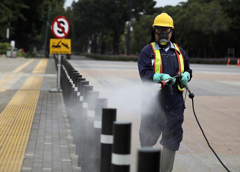 A worker sprays disinfectant at the pedestrian walkway at Senayan Sports Complex amid coronavirus outbreak, in Jakarta, Indonesia, Thursday, March 26, 2020. The new coronavirus causes mild or moderate symptoms for most people, but for some, especially older adults and people with existing health problems, it can cause more severe illness or death. (AP Photo/Dita Alangkara)