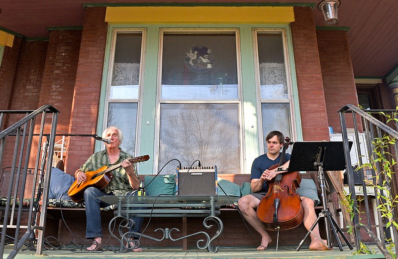Staff Photo by Robin Rudd / Jim Palmour plays and sings "Bristlecone Pine" as cellist Ben Van Winkle listens.  Residents of the Fort Wood Historic District took to their porches to share their musical talents as a way to ward off the tension of the coronavirus pandemic on March 27, 2020.