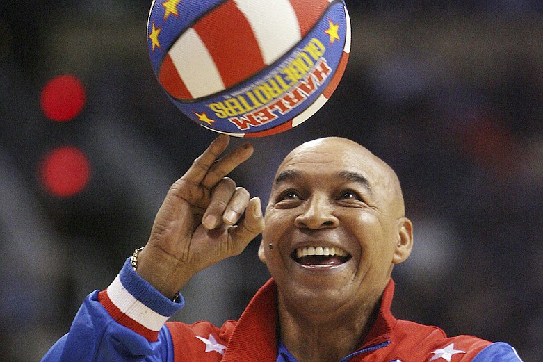In this Jan. 9, 2008, file photo, the Harlem Globetrotters' Fred "Curly" Neal performs during a timeout in the second quarter in an NBA basketball game between the Indiana Pacers and the Phoenix Suns in Phoenix. Neal, the dribbling wizard who entertained millions with the Harlem Globetrotters for parts of three decades, has died the Globetrotters announced Thursday, March 26, 2020. He was 77. Neal played for the Globetrotters from 1963-85, appearing in more than 6,000 games in 97 countries for the exhibition team known for its combination of comedy and athleticism. (AP Photo/Ross D. Franklin, File)