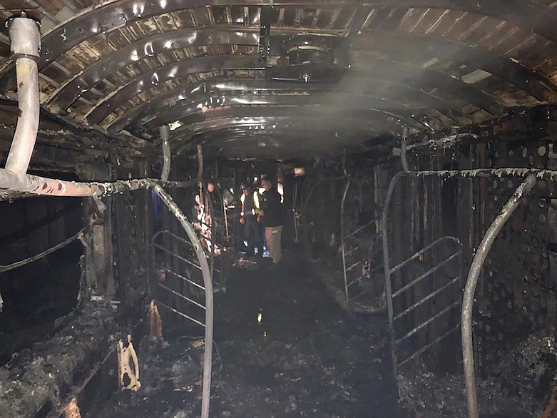In this Friday, March 27, 2020, photo provided by the Fire Department of the City of New York, authorities examine the remains of a subway car after it was destroyed by fire. Officials said a fire in a shopping cart on the subway train led to the death of the train's operator and injuries to several other people early Friday. The incident is being investigated as a crime. (FDNY via AP)