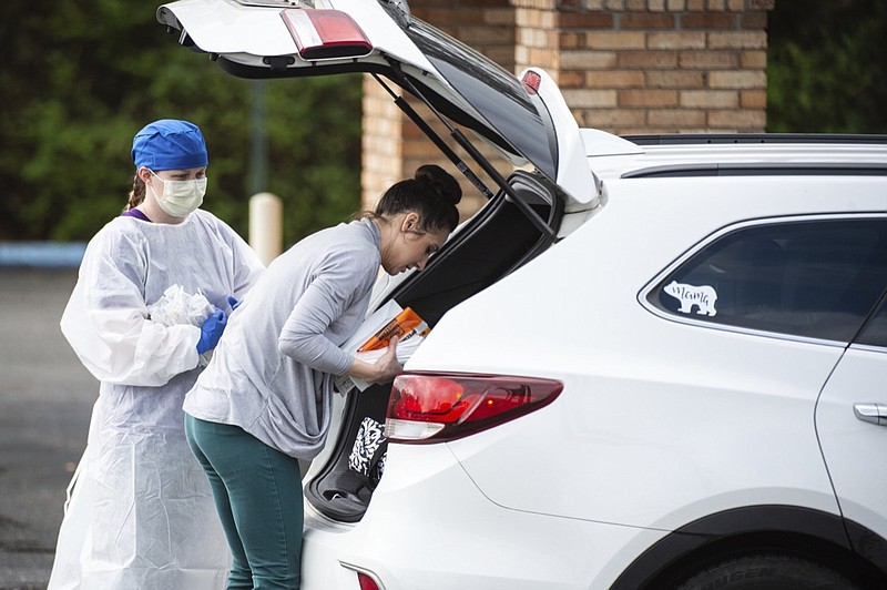 A woman delivers medical supplies at a screening clinic at Hartselle Family Practice, organized by Decatur Morgan Hospital, on Tuesday, March 24, 2020, in Hartselle, Ala. Those who meet the criteria for COVID-19 testing are sent to another site. (Dan Busey/The Decatur Daily via AP)