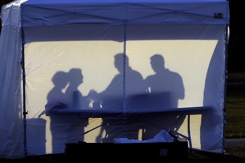 FILE - In this Wednesday, March 25, 2020 file photo, medical personnel are silhouetted against the back of a tent before the start of coronavirus testing in the parking lot outside of Raymond James Stadium in Tampa, Fla. As cases skyrocket in the U.S. and Europe, it's becoming more clear that how healthy you were before the pandemic began plays a key role in how you fare regardless of how old you are. (AP Photo/Chris O'Meara)

