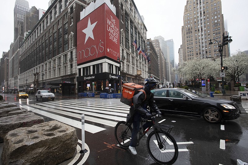 A cyclist passes Macy's in Herald Square, Monday, March 23, 2020, in New York. Macy's stores nationwide are closed due to the coronavirus. (AP Photo/Mark Lennihan)