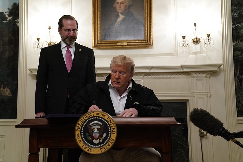 Photo by Evan Vucci of The Associated Press / President Donald Trump signs an $8.3 billion bill to fight the coronavirus outbreak in the U.S. on Friday, March 6, 2020 at the White House in Washington, as Department of Health and Human Services Secretary Alex Azar, looks on.