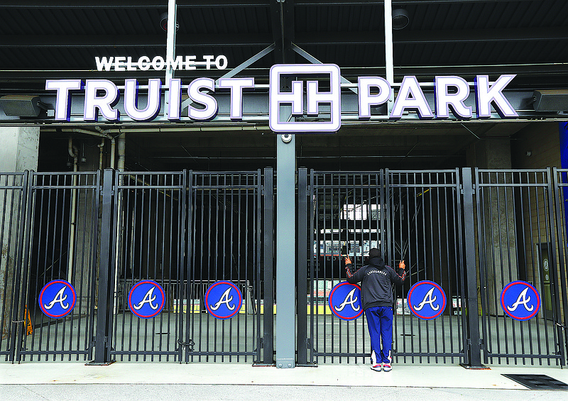 AP photo by Curtis Compton / Dwayne Jones looks through the gate of Truist Park, home of the Atlanta Braves, on March 16. Major League Baseball pushed back opening day until mid-May at the earliest because of the new coronavirus after the federal government recommended restricting events of more than 50 people for the next eight weeks.