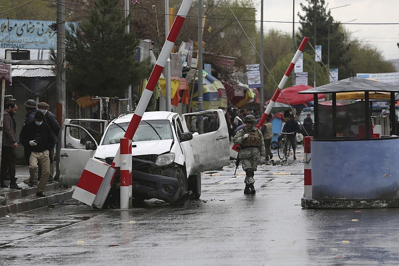 An Afghan security forces member looks at a damaged vehicle after an bomb explosion in Kabul, Afghanistan, Monday, March 30, 2020.  A sticky bomb attached to the vehicle detonated, according to Firdaus Faramraz, spokesman for the Kabul police chief. (AP Photo/Rahmat Gul)