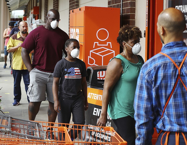 Customers wait in line to enter the Home Depot store at Midtown Place while the store limits the number of occupants to maintain six feet of space between shoppers and help prevent the spread of coronavirus on Sunday, March 29, 2020, in Atlanta. (Curtis Compton//Atlanta Journal-Constitution via AP)