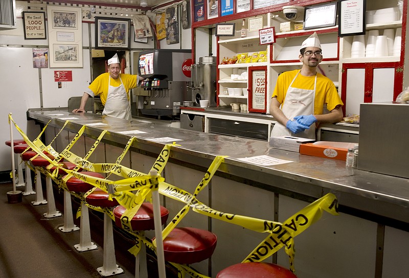 Texas Tavern employees Chris Dobe, left, and Nick Moore wait for take out orders on Monday night, March 30, 2020. Though customers are tipping well, and the diner is still open 24-7, Moore said they are making a quarter to a third less than what they normally do in tips. (Heather Rousseau/The Roanoke Times via AP)