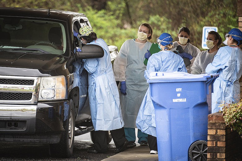 Medical personnel screen a patient at Hartselle Family Practice, organized by Decatur Morgan Hospital, on Tuesday, March 24, 2020, in Hartselle, Ala. Those who meet the criteria for COVID-19 testing are sent to another site. (Dan Busey/The Decatur Daily via AP)