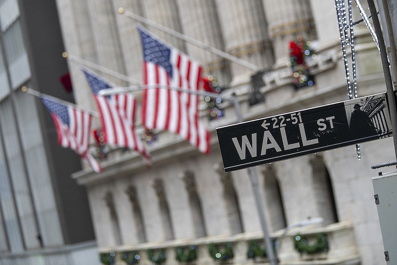 In this Jan. 3, 2020, file photo, the Wall St. street sign is framed by American flags flying outside the New York Stock Exchange in New York. Shares are down in European trading on Friday, March 27, and expected to drop on Wall Street as investors weigh news of more virus infections against the economic stimulus provided by world authorities. (AP Photo/Mary Altaffer, File)