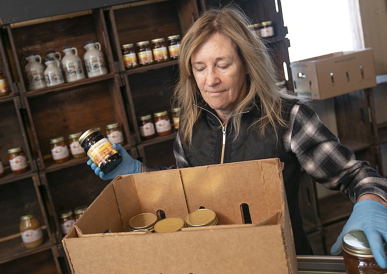 Linda DeFrancesco stocks shelves with her farm's own salsa, spreads, veggies and salsa at DeFrancesco Farm Stand in Northford, Conn., Thursday, March 26, 2020. Businesses across the state are worried about the impact of the coronavirus, even the ones considered "essential" like farmers' markets and garden centers. The farm stand opens Saturday at 10 a.m. (Dave Zajac/Record-Journal via AP)