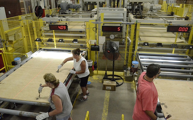 Staff file photo / Employees at a Shaw Industries hardwood flooring plant work on a part of the production process.