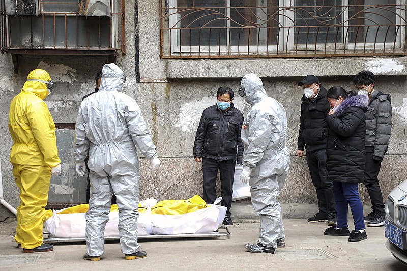 FILE - In this Feb. 1, 2020, file photo, funeral home workers remove the body of a person suspected to have died from the coronavirus outbreak from a residential building in Wuhan in central China's Hubei Province. Skepticism about China's reported coronavirus cases and deaths has swirled throughout the crisis, fueled by official efforts to quash bad news in the early days and a general distrust of the government. In any country, getting a complete picture of the infections amid the fog of war is virtually impossible. (Chinatopix via AP, File)


