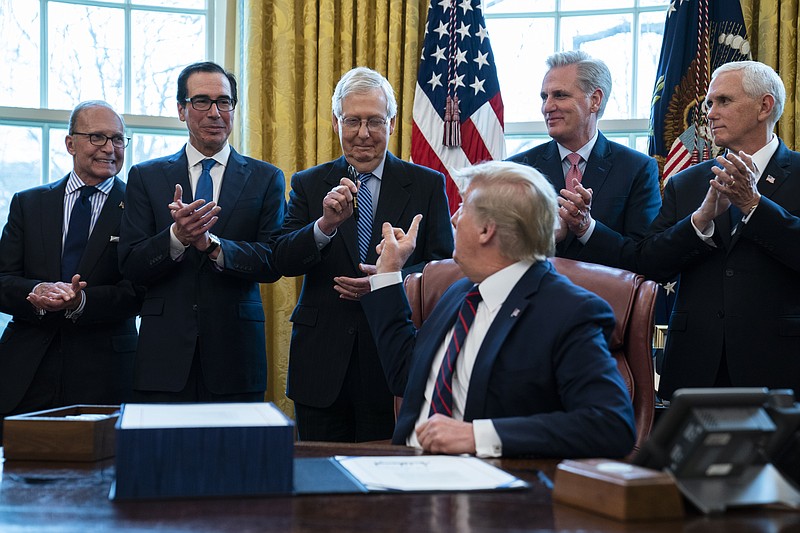 President Donald Trump hands a pen to Senate Majority Leader Mitch McConnell of Kentucky., after signing the coronavirus stimulus relief package in the Oval Office at the White House. From left are White House chief economic adviser Larry Kudlow, Treasury Secretary Steven Mnuchin, McConnell, Trump, House Minority Leader Kevin McCarty, R-Calif., and Vice President Mike Pence.