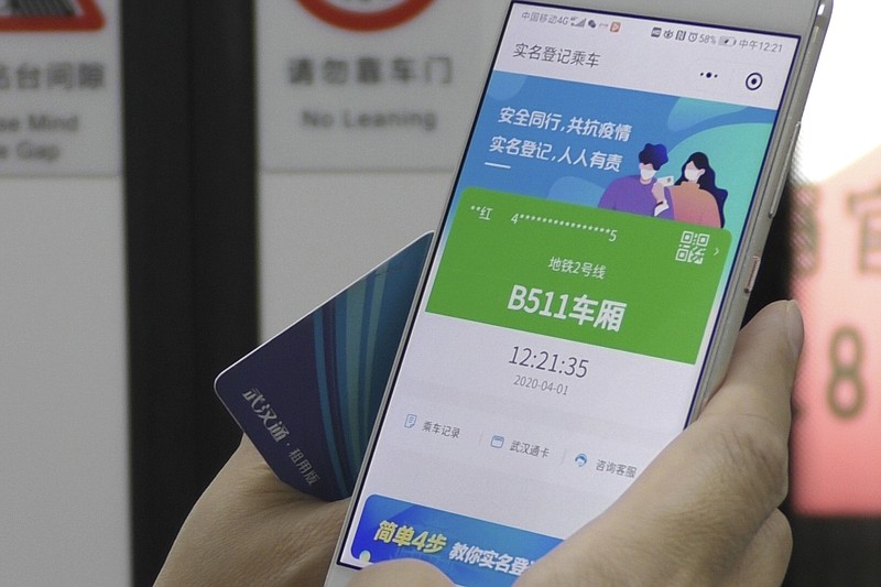 In this April 1, 2020, photo, a passenger holds up a green pass on their phone on a subway train in Wuhan in central China's Hubei province. Green is the "health code" that says a user is symptom-free and it's required to board a subway, check into a hotel or just enter Wuhan, the central city of 11 million people where the pandemic began in December. (AP Photo/Olivia Zhang)



