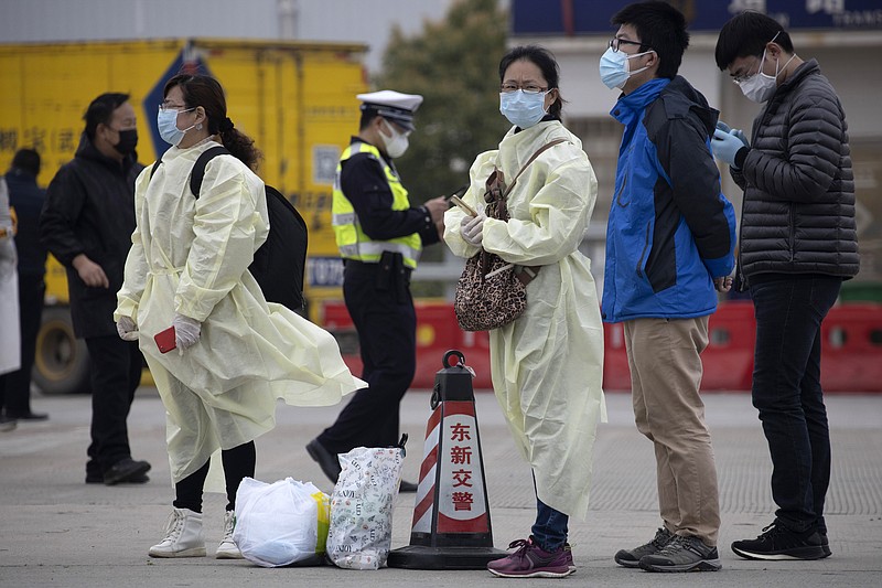 Residents wearing protective gear wait near a toll booth where some are entering the city of Wuhan which is still under lockdown due to the coronavirus outbreak but have started allowing some residents to return in central China's Hubei province on Thursday, April 2, 2020. (AP Photo/Ng Han Guan)