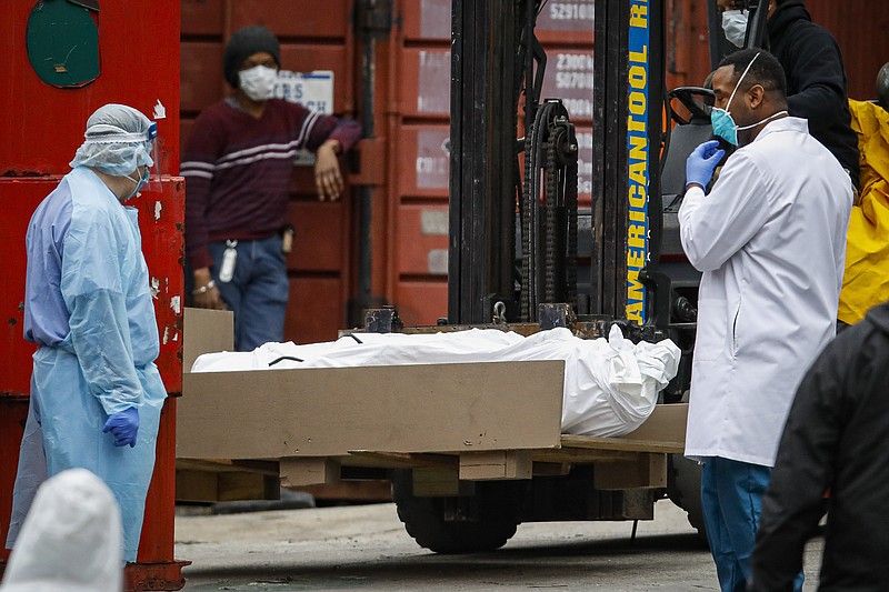 A body wrapped in plastic is prepared to be loaded onto a refrigerated container truck used as a temporary morgue by medical workers due to COVID-19 concerns, Tuesday, March 31, 2020, at Brooklyn Hospital Center in the Brooklyn borough of New York. The new coronavirus causes mild or moderate symptoms for most people, but for some, especially older adults and people with existing health problems, it can cause more severe illness or death. (AP Photo/John Minchillo)


