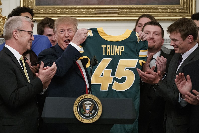 AP photo by Carolyn Kaster / President Donald Trump holds a jersey presented by the North Dakota State football team, which won the 2018 FCS national title, during a ceremony at the White House on March 4, 2019.