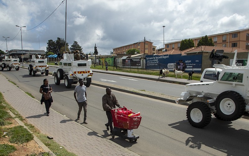 A man pushing a shopping cart with food on the street as South African National Defence Forces drive through a densely populated Alexandra township east of Johannesburg, South Africa, Saturday, March 28, 2020. South Africa went into a nationwide lockdown for 21 days in an effort to control the spread of the COVID-19 coronavirus. The new coronavirus causes mild or moderate symptoms for most people, but for some, especially older adults and people with existing health problems, it can cause more severe illness or death. (AP Photo/Themba Hadebe)