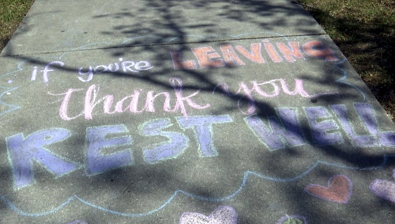 This March 26, 2020 image from video shows a message written in chalk that says, "If you're leaving, thank you, rest well," on a sidewalk at Ochsner Medical Center in New Orleans. (AP Photo/Stacey Plaisance)