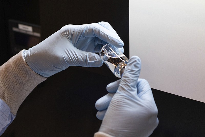 In this March 2020 photo provided by Gilead Sciences, a vial of the investigational drug remdesivir is visually inspected at a Gilead manufacturing site in the United States. Given through an IV, the medication is designed to interfere with an enzyme that reproduces viral genetic material. (Gilead Sciences via AP)