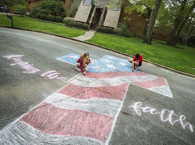 Layne Bjornseth, left, and her boyfriend Ben Glover touch up a mural with chalk off Southampton Court on Monday, March 30, 2020, in Decatur, Ala. Bjornseth's inspiration for the artwork is to share a message of hope and encouragement the coronavirus pandemic. (Dan Busey/The Decatur Daily via AP)