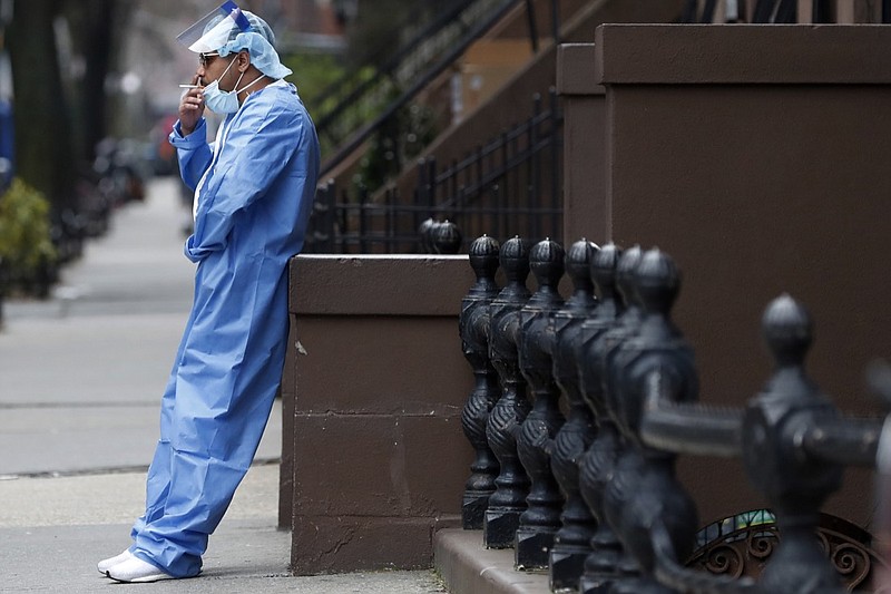 Wearing his personal protective equipment, emergency room nurse Brian Stephen leans against a stoop as he takes a break from his work at the Brooklyn Hospital Center, Sunday, April 5, 2020, in New York. Located in downtown Brooklyn, the hospital is one of several in the New York area that has been treating high numbers of coronavirus patients during the pandemic. (AP Photo/Kathy Willens)