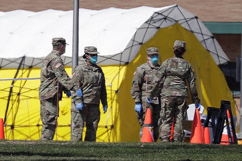 Members of the National Guard congregate outside a tent next to Sunny Ridge nursing home, Sunday, April 5, 2020, in Sheboygan, Wis. Health officials say a second person has died in a coronavirus outbreak at a nursing home in Sheboygan. The death at Sunny Ridge Nursing and Rehabilitation Center was announced Sunday as the Wisconsin National Guard arrived to begin testing all staff and more than 90 residents. (Gary Klein/The Sheboygan Press via AP)