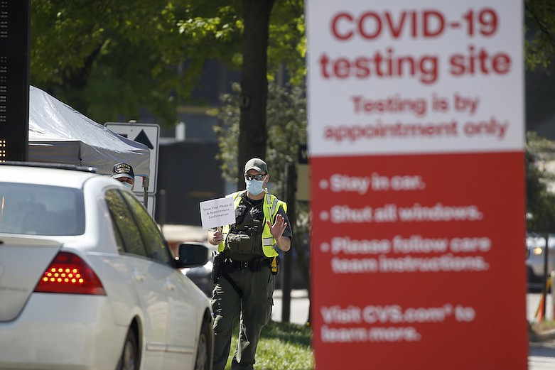 A police officer directs cars into a coronavirus testing facility at Georgia Tech Monday, April 6, 2020, in Atlanta. The testing is by appointment only and requires a referral. (AP Photo/John Bazemore)