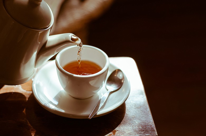 Pot of hot tea being poured into a tea cup. / Getty Images/iStock/WiroKlyngz