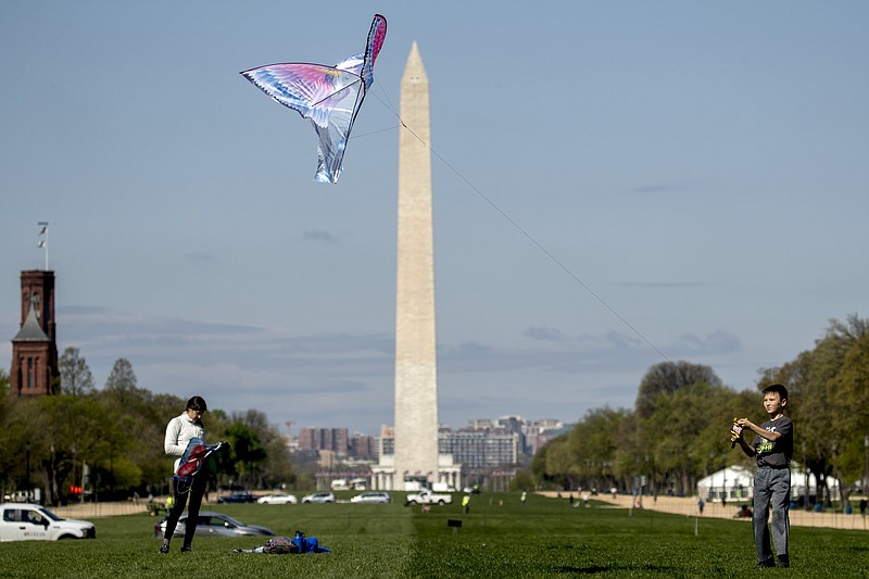 In this April 6, 2020 photo, the Washington Monument is visible behind a boy as he flies a kite on the National Mall in Washington. The warmer weather is bringing increased violations of social distance guidelines in the nation's capital, even as health officials predict that Washington could become one of the next U.S. hot spots in the coronavirus pandemic. (AP Photo/Andrew Harnik)

