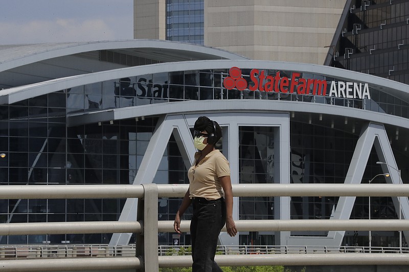 A person wearing a mask walks near the StateFarm Arena where the men's Final Four NCAA college basketball championship game was to be played on Monday, April 6, 2020, in Atlanta. The entire NCAA tournament was canceled due to the COVID-19 virus. (AP Photo/Brynn Anderson)



