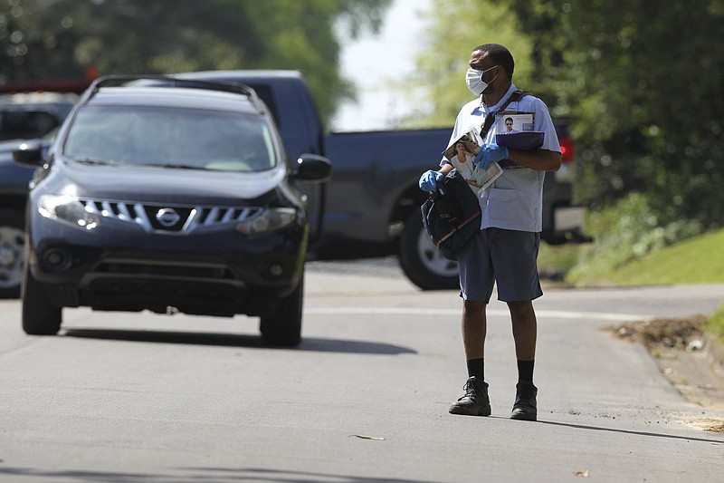 In this Monday, April 6, 2020 photo, U.S. postal carrier Hakeem Watson wears both gloves and a mask as he delivers the mail to homes along Magnolia Street in Tupelo, Miss. (Thomas Wells/The Northeast Mississippi Daily Journal via AP)


