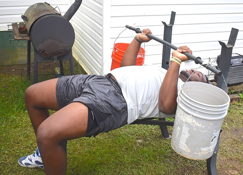 Staff photo by Patrick MacCoon / Red Bank High School junior BJ Ragland lifts buckets filled with sand and rocks in his backyard on Wednesday. Ragland has received more than a dozen football scholarship offers in close to a month.