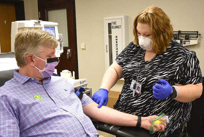 Staff Photo by Robin Rudd / Blood Assurance Assistant Team Leader Stephee Haun locates a vein to use in Dr. Barnes's left arm.  Dr. Stephen Barnes, who recovered from coronavirus, is donated his plasma to help patients fight COVID-19 infections at Blood Assurance on April 9, 2020.  