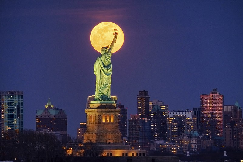 FILE - In this March 9, 2020, file photo, the full moon rises behind the Statue of Liberty in New York. From California to Colorado to Georgia and New York, Americans are taking a moment each night at 8 to howl to thank the nation's health care workers and first responders for their selfless sacrifices during the coronavirus pandemic. (AP Photo/J. David Ake, File)


