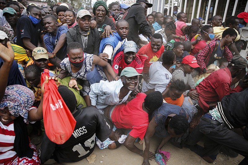 Residents desperate for a planned distribution of food for those suffering under Kenya's coronavirus-related movement restrictions push through a gate and create a stampede, causing police to fire tear gas and leaving several injured, at a district office in the Kibera slum, or informal settlement, of Nairobi, Kenya, Friday, April 10, 2020. (AP Photo/Brian Inganga)


