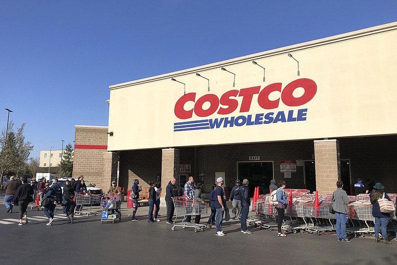 FILE - In this March 20, 2020 file photo, shoppers line up to enter a Costco store in Tacoma, Wash. Americans are beginning to see the first economic impact payments hit their bank accounts this week. (AP Photo/Ted S. Warren, Fle)