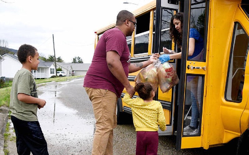 Staff Photo by Robin Rudd / School bus driver Melisa Giles makes a delivery to Chris Dee and his children Patty and Malachi.  Dade County Schools are delivering meals to students by bus at least twice a week while kids are out of town. 