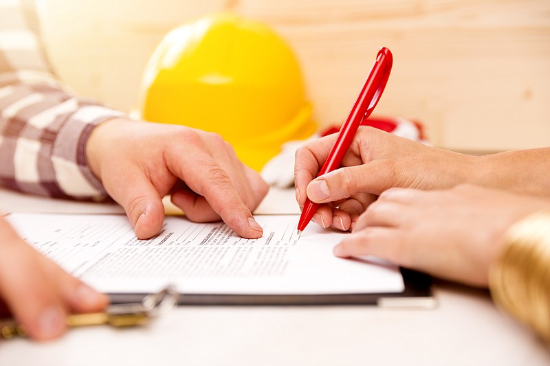 Woman signing construction contract with contractor to build a house contractor tile / Getty Images
