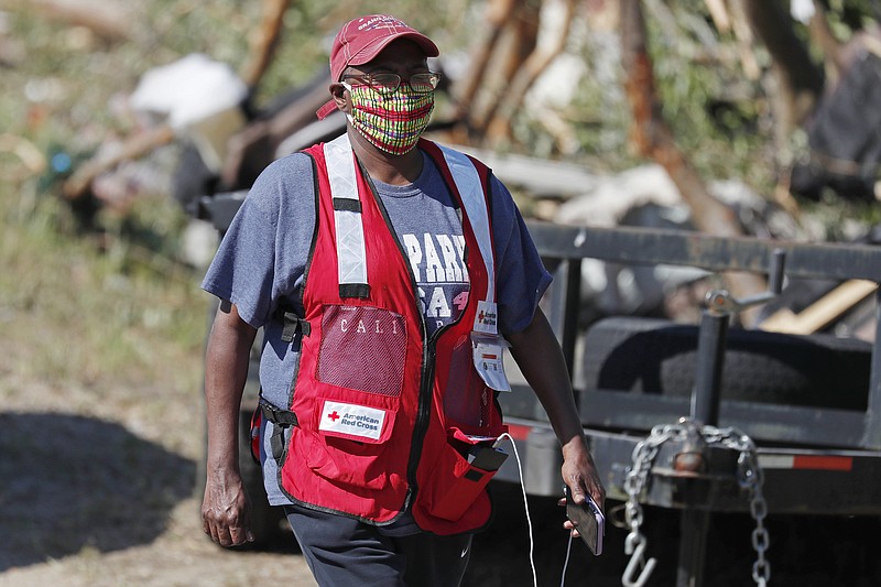 Red Cross volunteer Katherine Campbell Hudson wears her face mask as she visits tornado damaged residences in this south Prentiss, Miss., neighborhood, Tuesday, April 14, 2020, as recovery from Sunday's tornado continues. (AP Photo/Rogelio V. Solis)