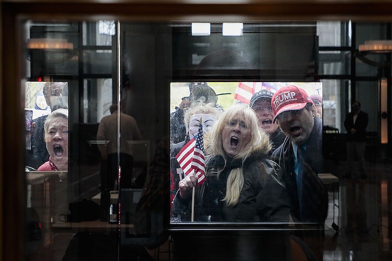 In this April 13, 2020, file photo Ohio state senate candidate Melissa Ackison, left, and other protesters stand outside the Statehouse Atrium where reporters listen during the State of Ohio's Coronavirus response update at the Ohio Statehouse in Columbus, Ohio. The unprecedented national effort to shut down much of daily life to slow the spread of COVID-19 is prompting a growing number of protests. (Joshua A. Bickel/The Columbus Dispatch via AP, File)