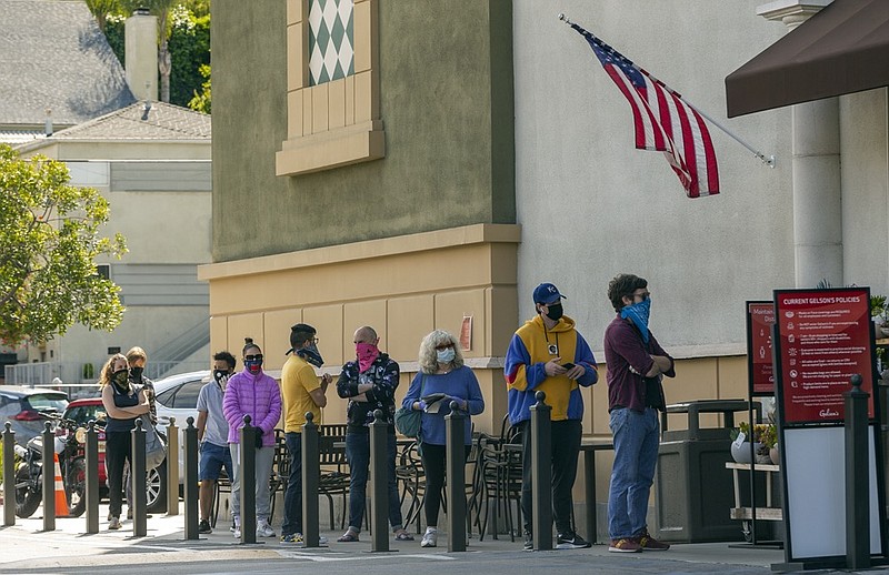 Customers wearing face masks line up outside Gelson's Market while saying apart during the coronavirus pandemic, in the Los Feliz area of Los Angeles on Friday, April 17, 2020. (AP Photo/Damian Dovarganes)


