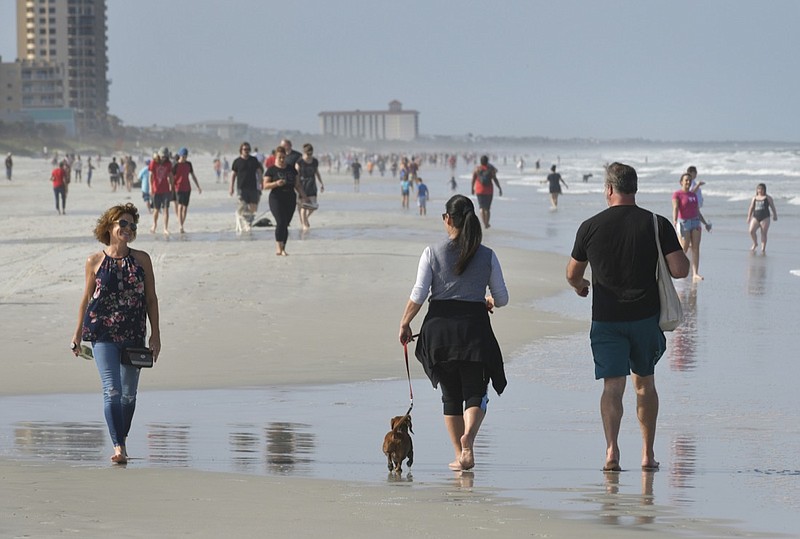 People walk on the beach during the coronavirus pandemic Friday, April 17, 2020 on Jacksonville Beach, Fla. Gov. Ron DeSantis has given the green light for some beaches and parks to reopen if it can be done safely after being closed because of the coronavirus. DeSantis' announcement on Friday came as north Florida beaches became among the first to allow beach-goers to return since the closures. (Will Dickey/The Florida Times-Union via AP)