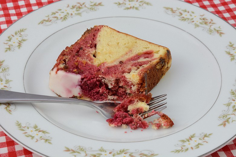 Red strawberry marbled pound cake with bits of chocolate with icing and fork on white plate. / Getty Images/iStock/Merrimon